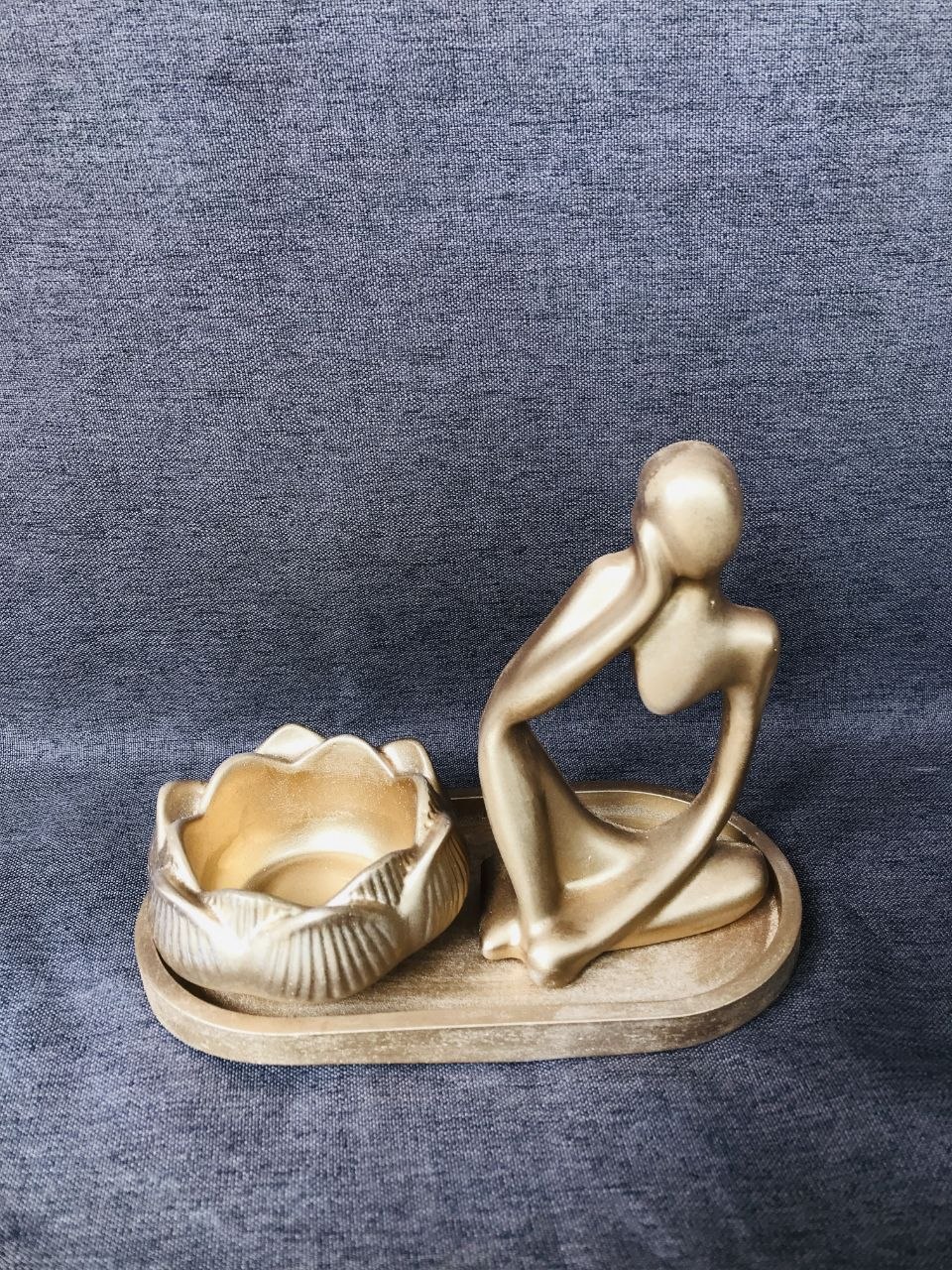 Gold-tone sculptural figure and petal-shaped accent arranged on a tray