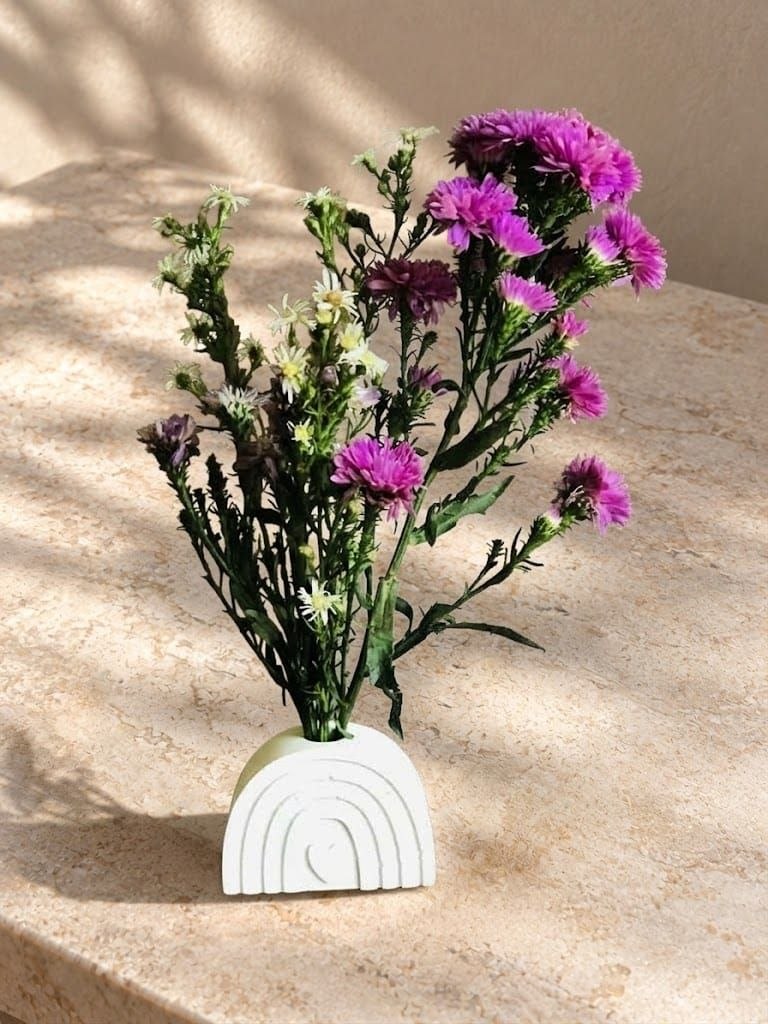 Arched sculptural vase styled with small flowers in natural light