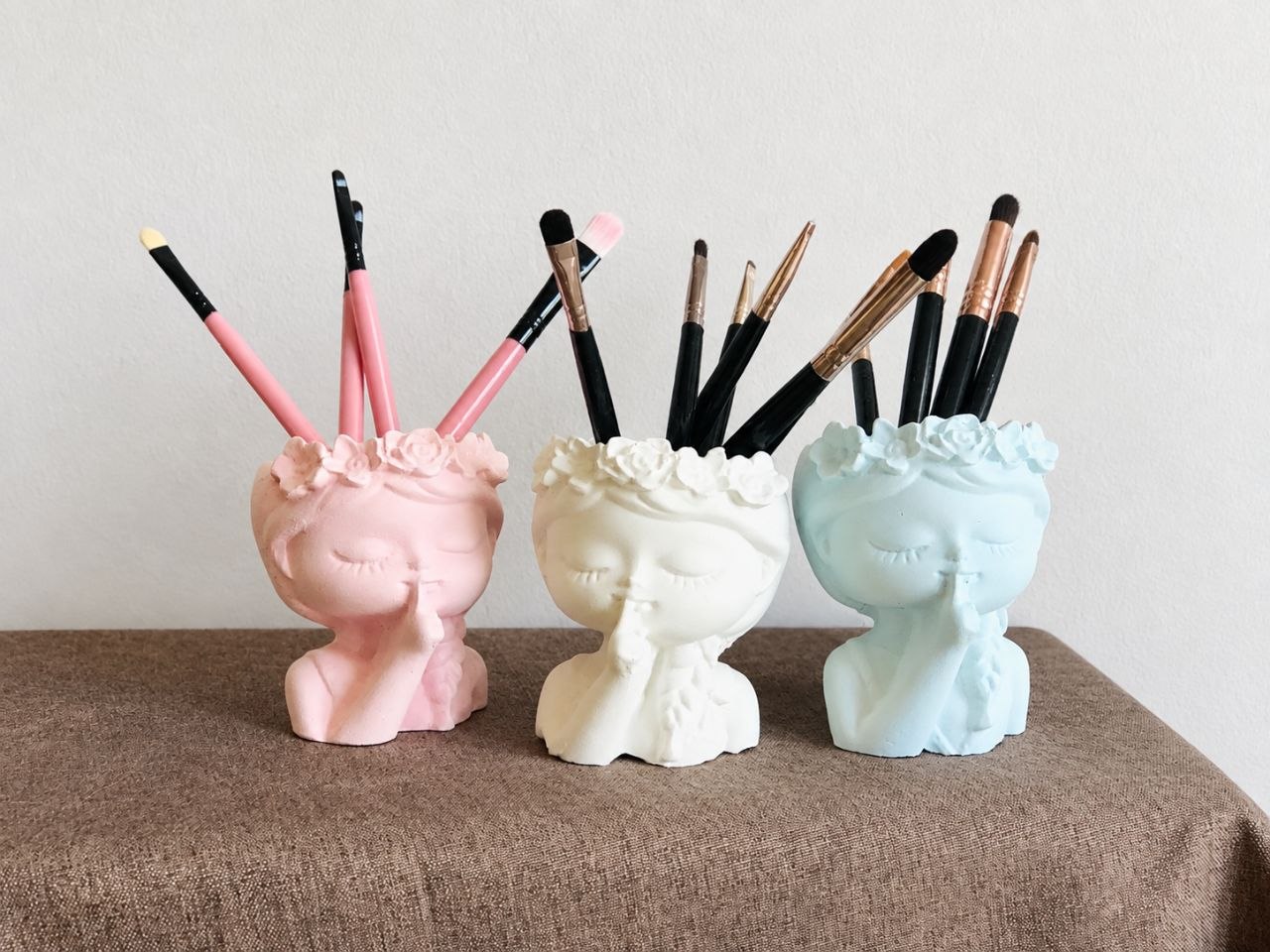 Pastel face-shaped holders arranged with cosmetic brushes
